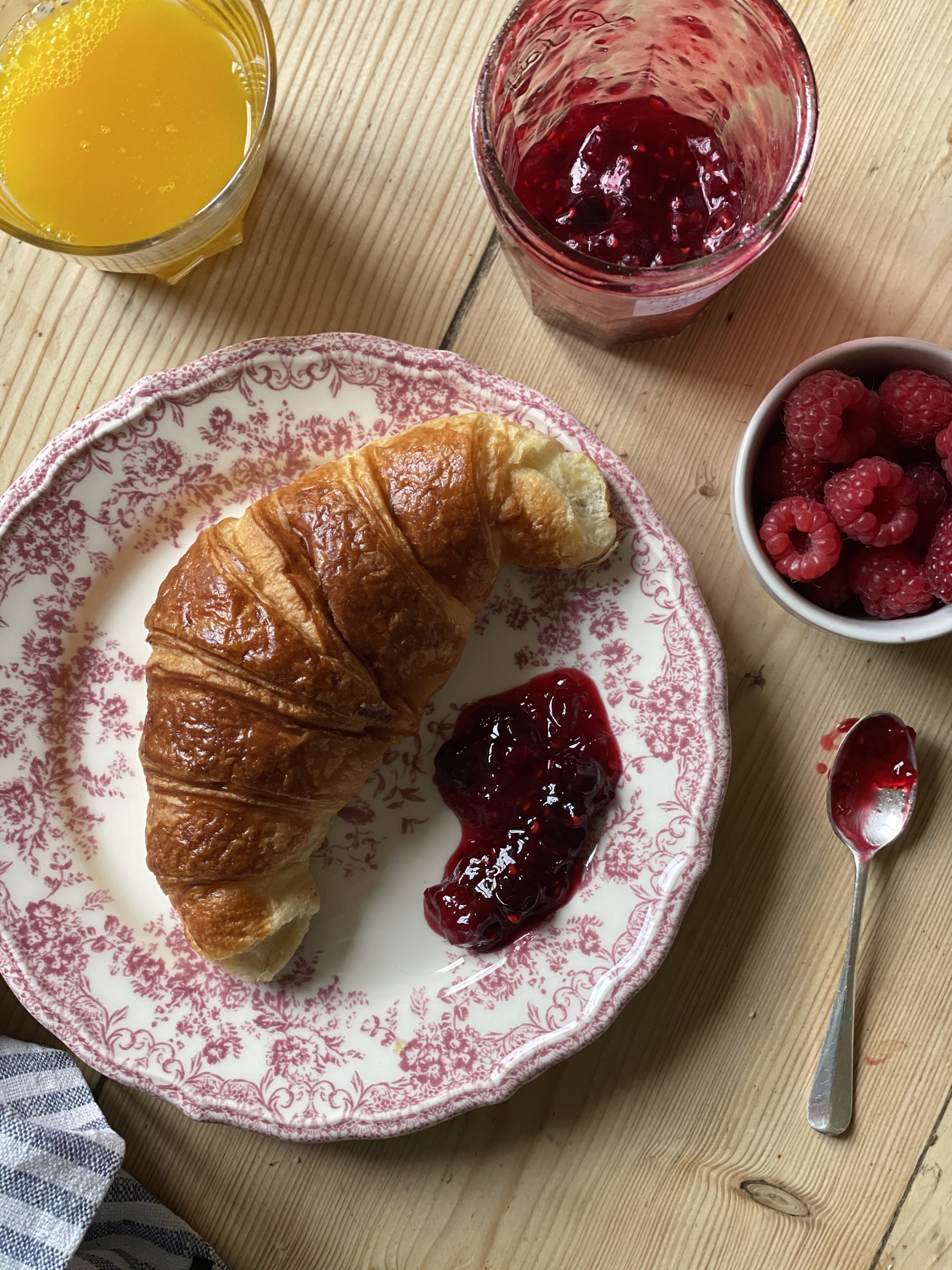 Summer berry jam on with a fresh flaky croissant served from breakfast with orange juice.